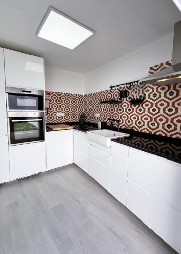 a kitchen with white cabinets and a patterned wall at Casa Dos Borrachos in Aldeia do Mato