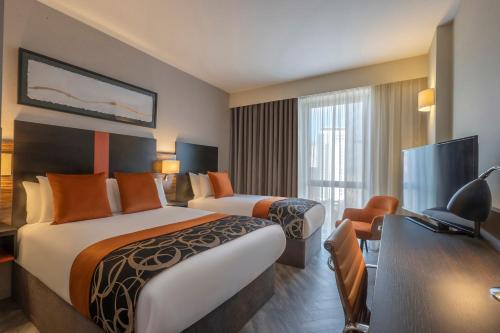 ein Hotelzimmer mit 2 Betten und einem Schreibtisch in der Unterkunft Clayton Hotel Cardiff in Cardiff