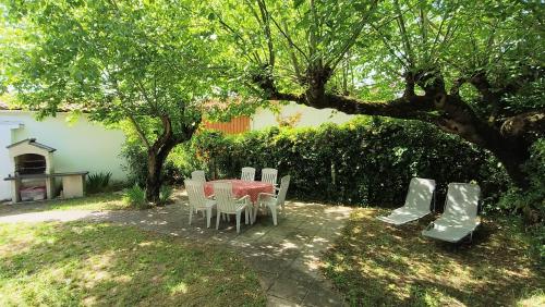 une table et des chaises sous un arbre dans une cour dans l'établissement Maison Sarah Bernhardt tout confort, à Andernos-les-Bains