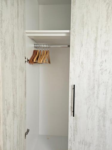 a room with a white wall and a closet with wooden hangers at Apartman Sky in Sremska Mitrovica