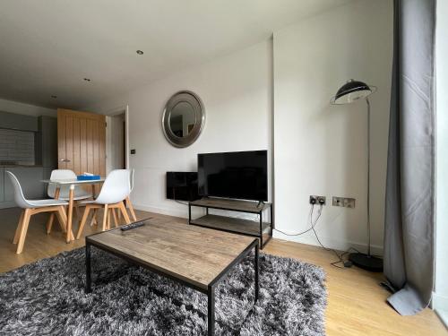 a living room with a table and a television at Stylish and Modern 2BR Apartment with Parking in Sheffield