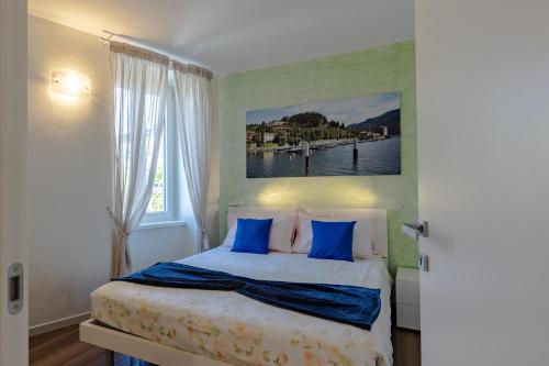 a bedroom with a bed with blue pillows and a window at Villa Vitali - Bellagio in Bellagio