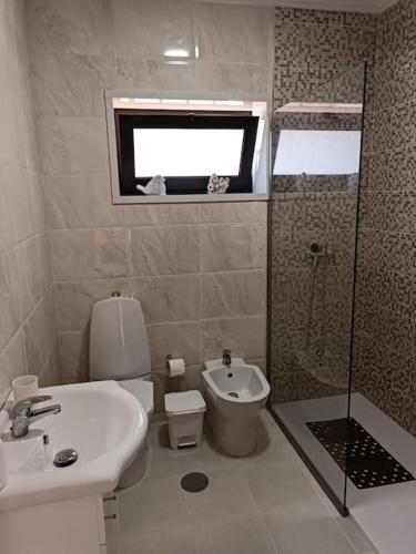 a bathroom with a toilet and a sink and a shower at Casa da Mimosa, a 100 metros da praia de Vila Chã in Vila Chã