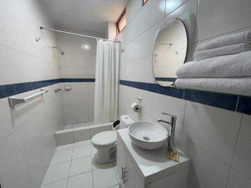 een badkamer met een toilet, een wastafel en een spiegel bij Posada Miraflores in Lima