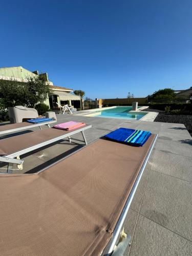 two beds on a patio next to a swimming pool at Sun Holidays Home in Marina di Modica