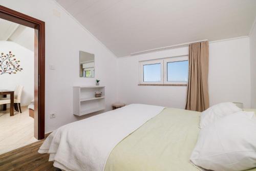 a white bedroom with a bed and a window at House Ljerka in Barbat na Rabu