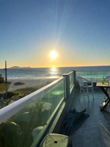 a balcony with a view of the ocean at sunset at Central Praias III in Cabo Frio