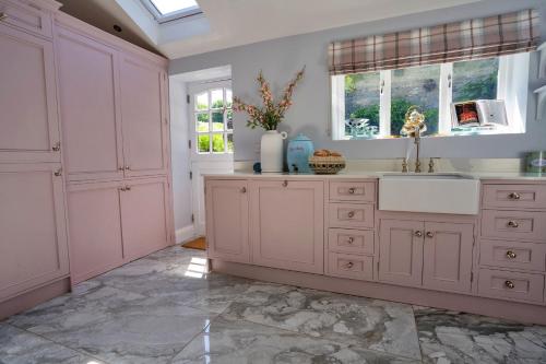 a kitchen with pink cabinets and a sink at Finest Retreats - Sisu Bakewell, Limestones Cottage in Bakewell