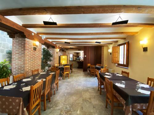 um restaurante com mesas e cadeiras e uma parede de tijolos em HOTEL EL RASTRO - Palacio Duque de Tamames - em Ávila
