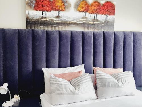 a couch with pillows and a painting of trees at Lions Haven in Pretoria