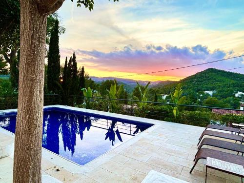 una piscina con un árbol y una puesta de sol en Stylish luxury villa near Sitges, en Olivella