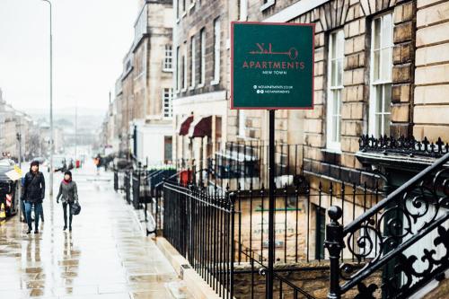 a sign on a street with people walking down the street at No1 Apartments Edinburgh - New Town in Edinburgh
