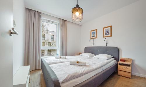 een slaapkamer met een groot bed met witte lakens bij NADMORSKI NAVIO APARTMENT PRZY PLAŻY in Gdańsk