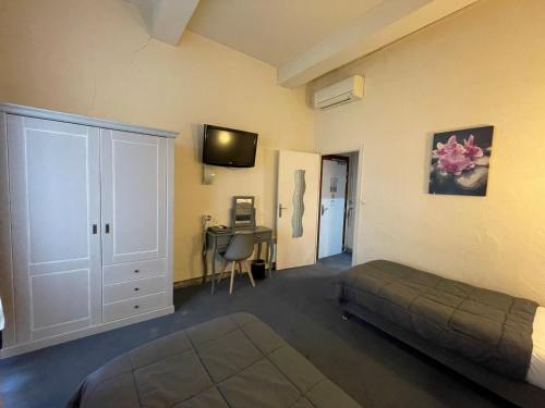 Schlafzimmer mit einem Bett, einem Schreibtisch und einem TV in der Unterkunft Hotel De France in Perpignan