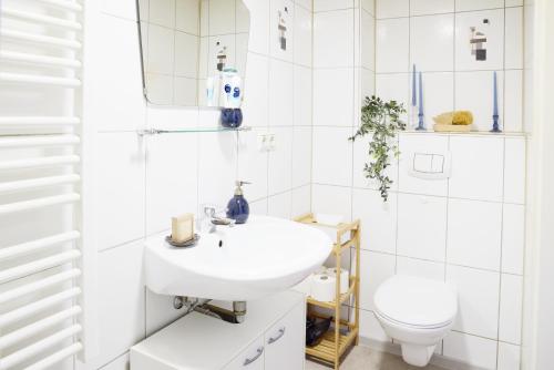 a white bathroom with a sink and a toilet at IDEE Living: City Apartment am Marktplatz in Heppenheim an der Bergstrasse