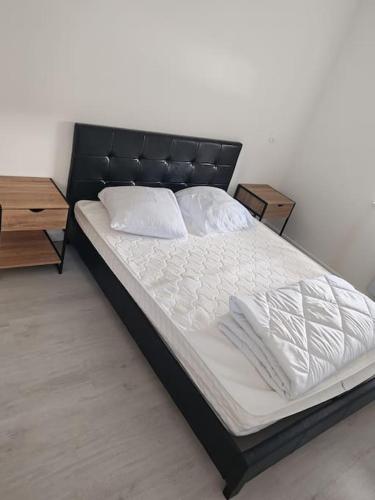 - un lit avec une tête de lit noire ainsi que des draps et des oreillers blancs dans l'établissement Maison de campagne, à Fenneviller