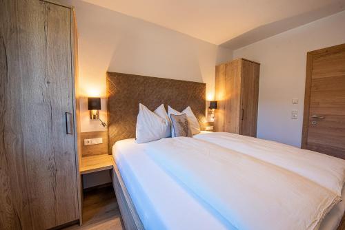 a bedroom with a large white bed with a wooden headboard at AppartMO - Zillertal Arena, Hohe Tauern, Salzburgerland, Krimml, Hochkrimml in Krimml