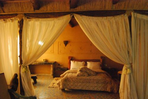 a bedroom with a canopy bed with white curtains at Hotel Taddart in Midelt