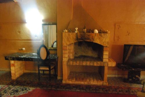 a living room with a fireplace with a table and a chair at Hotel Taddart in Midelt