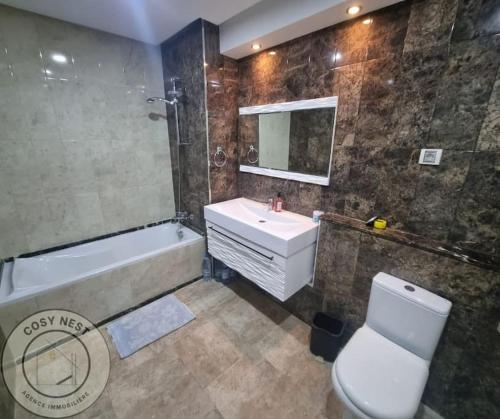 a bathroom with a sink and a tub and a toilet at Appartement vue sur mer in Sousse