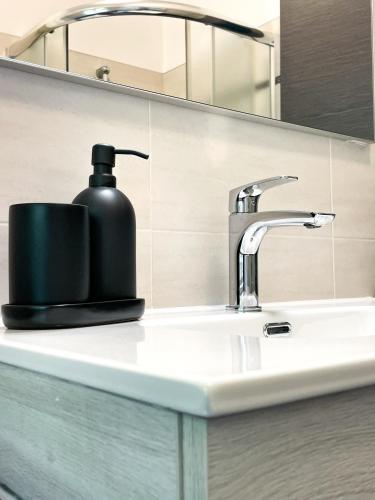 a bathroom sink with a black soap dispenser on it at Due Pini Apartment - Ponte Caffaro Lake Idro in Ponte Caffaro