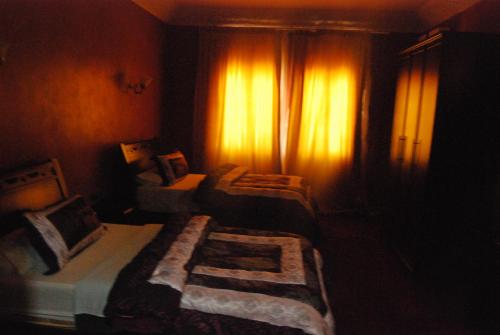 a dark room with two beds and a window at Hotel Taddart in Midelt