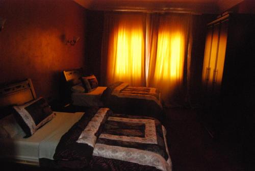 a bedroom with two beds in a dark room at Hotel Taddart in Midelt