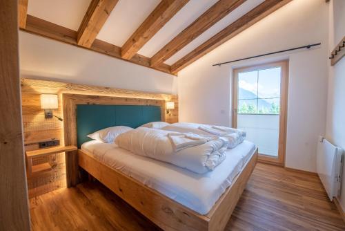 - une chambre avec un grand lit dans une pièce dotée d'une fenêtre dans l'établissement Filzsteinresort Chalets - Chalet 238, à Krimml