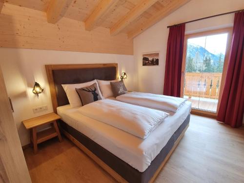 une chambre avec un grand lit avec une grande fenêtre dans l'établissement Filzsteinresort Chalets - Chalet 240, à Krimml