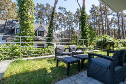 a patio with chairs and tables in the grass at Baltic Apartments in Pobierowo