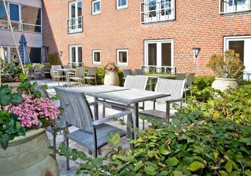 a patio with a table and chairs and flowers at Montra Hotel Sabro Kro in Sabro