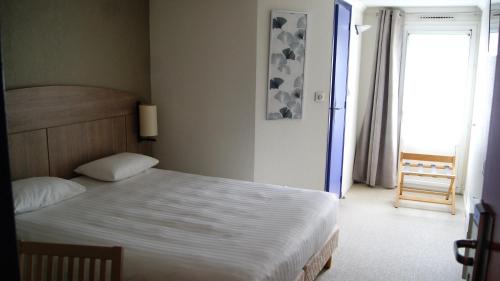 a bedroom with a large bed and a window at The Originals City, Hôtel Le Gayant, Douai in Douai