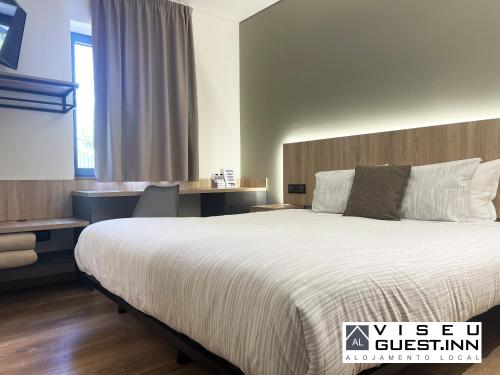 a hotel room with a large bed and a desk at Viseu Guest Inn in Viseu