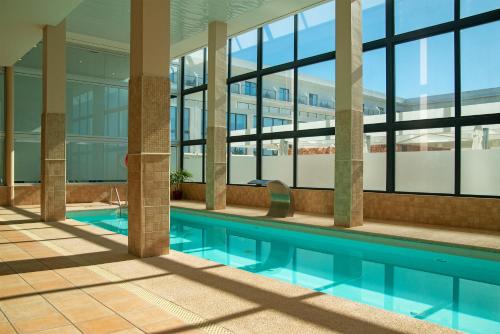 a swimming pool in a building with windows at Cabogata Beach Hotel in Retamar