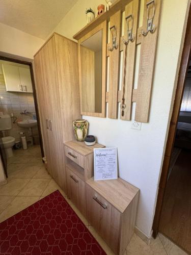 a bathroom with wooden cabinets and a sign in it at Apartments Aida in Bihać