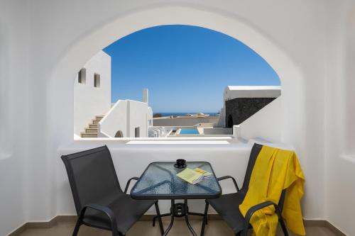 a table and chairs in a room with a window at Montrez Santorini - 2 Bedroom Apartment in Mesaria