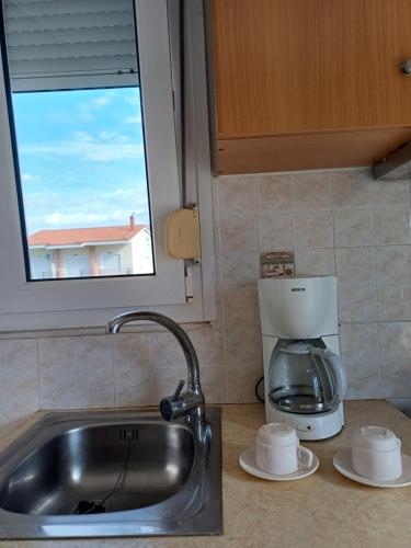 a kitchen counter with a sink and a coffee maker at Aktaion apartments in Artemísion