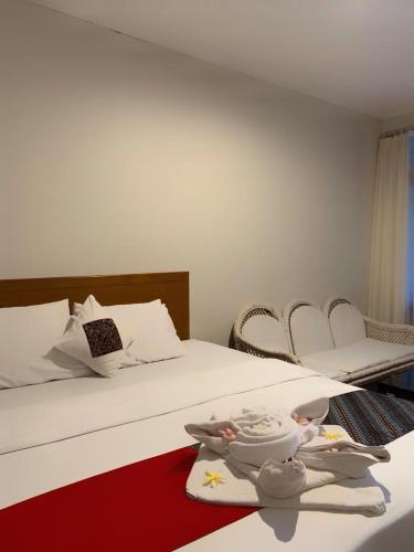 a bedroom with a white bed with a red blanket and chairs at Kusma Hotel Bandungan Semarang in Semarang