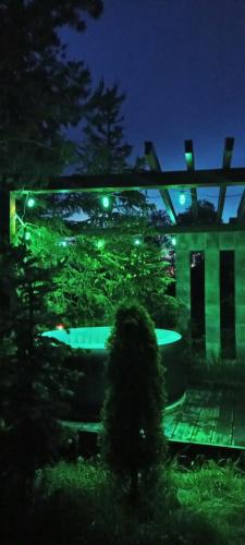 una casa illuminata di notte con luci verdi di Lux Houses w DOMKU tylko DWA APARTAMENTYz jacuzzi zewnętrznym a Groń