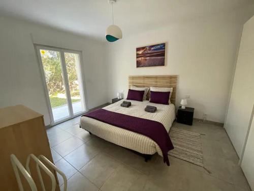 a bedroom with a large bed with purple pillows at Casa Sognu di Orizonte in Figari