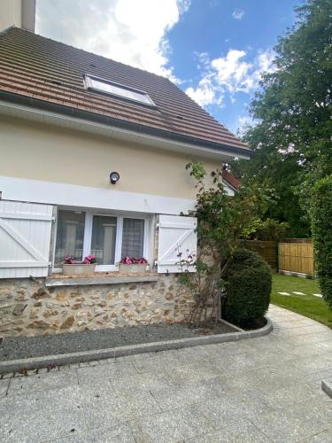 une maison avec des fenêtres blanches et un mur en pierre dans l'établissement Maisonnette avec jardin, à Domont