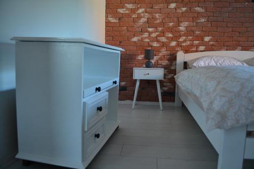 a bedroom with a bed and a dresser and a brick wall at Una Apartment Cetinje in Cetinje