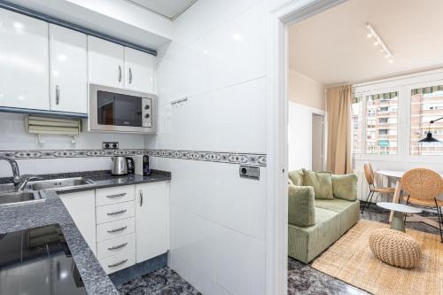 een keuken met witte kasten en een woonkamer bij 3 Bdr Apt In Cornella 5 Mins Form The Metro in Cornellà de Llobregat