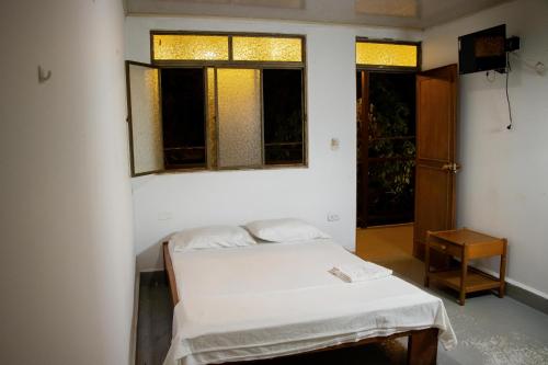 ein kleines Zimmer mit einem Bett und zwei Fenstern in der Unterkunft Casa Turística Macarena Tierra salvaje in La Macarena