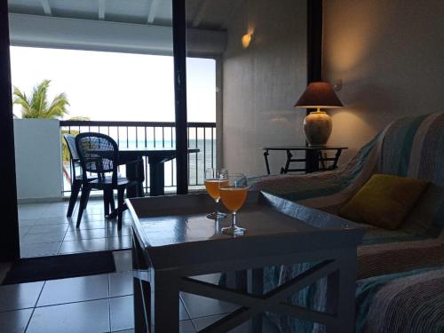 a living room with a table with two glasses on it at Une terrasse pleine vue mer in Le Gosier
