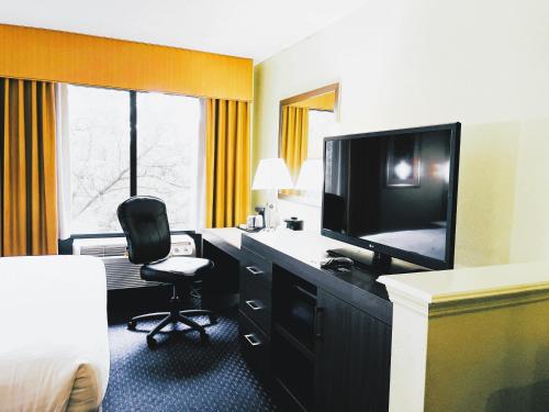 Habitación de hotel con TV y escritorio con silla. en Park Inn by Radisson Albany, en Albany