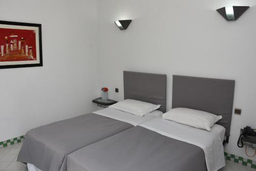 2 camas individuais num quarto com uma fotografia na parede em Appart-Hôtel Tagadirt em Agadir
