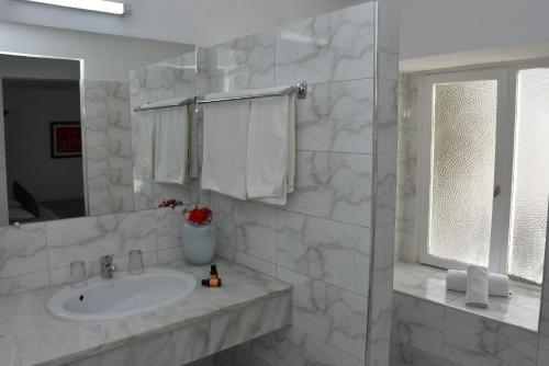 bagno bianco con lavandino e specchio di Appart-Hôtel Tagadirt ad Agadir