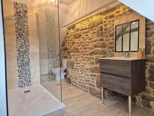 La salle de bains aux murs en pierre est pourvue d'un lavabo et d'une douche. dans l'établissement Gîte Gaïa au cœur de la campagne, à Le Champ-de-la-Pierre