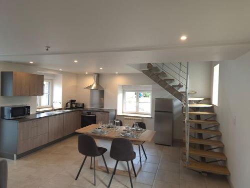 une cuisine avec une table et des chaises ainsi qu'un escalier dans l'établissement Gîte Gaïa au cœur de la campagne, à Le Champ-de-la-Pierre